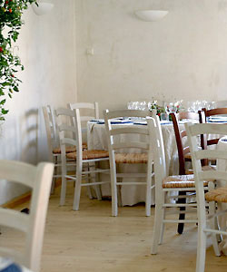 Weiße Stühle und Tische in einem weißen Raum mit hellem Holzboden