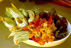 Gelbe Schale mit Zucchiniblüten, Kapuzinerkresseblüten und Artischocken